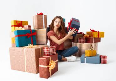 young-curly-woman-sitting-floor-gift-boxes-guessing-what-is-inside_176420-8171
